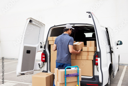 Delivery man loading van on parking lot photo