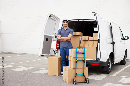 Confident delivery man near van with parcels photo