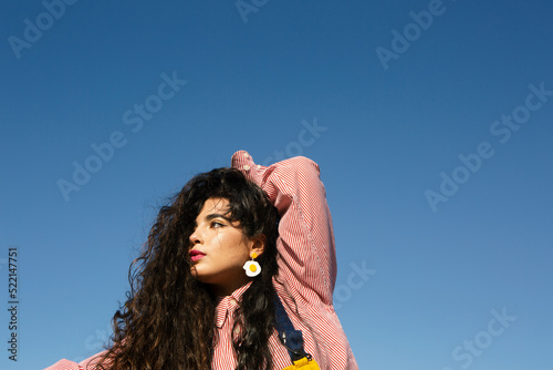 Young girl with long black curly hair posing under the blue sky photo