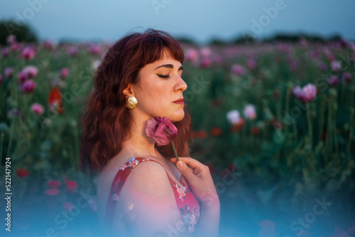 Moody Portrait Of Redhead Woman Holding A Poppy Flower photo