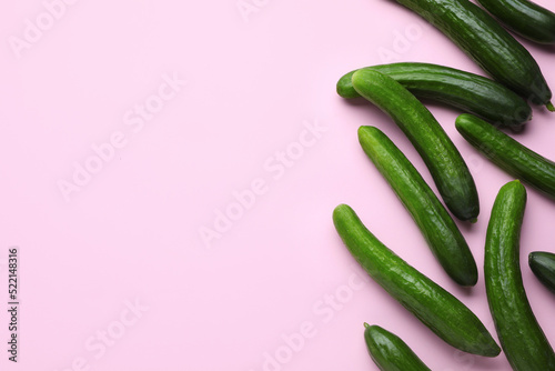Fresh ripe cucumbers on pink background, flat lay. Space for text