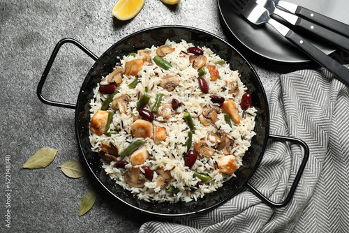 Delicious rice pilaf with chicken and vegetables on grey table, flat lay