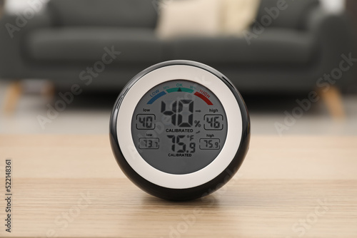 Digital hygrometer with thermometer on wooden table in room photo