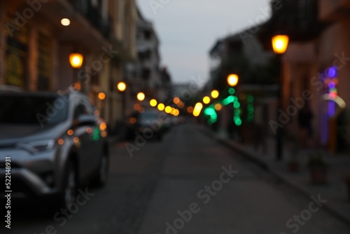 Blurred view of city street with parked cars in evening