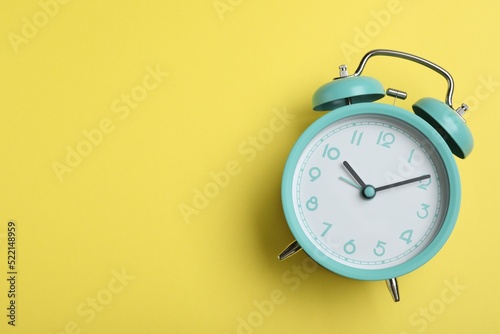 Alarm clock on yellow background, top view with space for text. School time