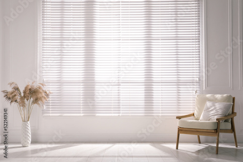 Obraz na plátne Cosy armchair and decor near large window with blinds in spacious room