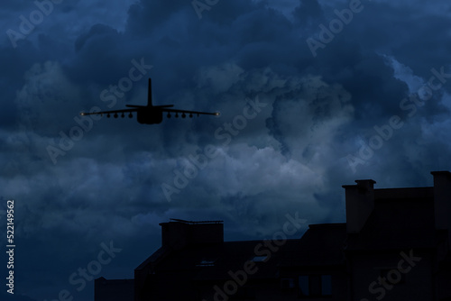 Silhouette of jet fighter in cloudy sky at night