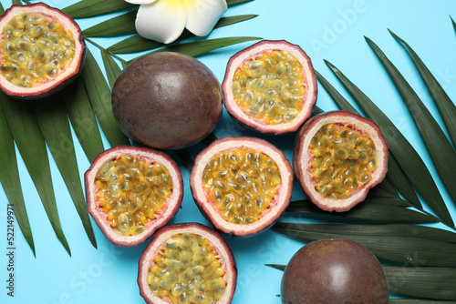 Passion fruits (maracuyas), flower and palm leaves on light blue background, flat lay photo