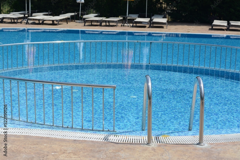 Outdoor swimming pool with ladder and railing on sunny day
