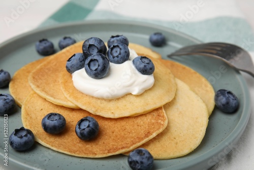 Tasty pancakes with natural yogurt and blueberries on table, closeup
