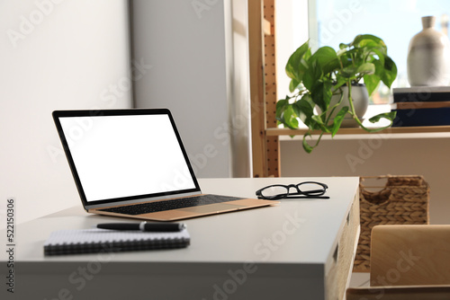 Workplace with modern laptop and glasses on white table. Mockup for design © New Africa