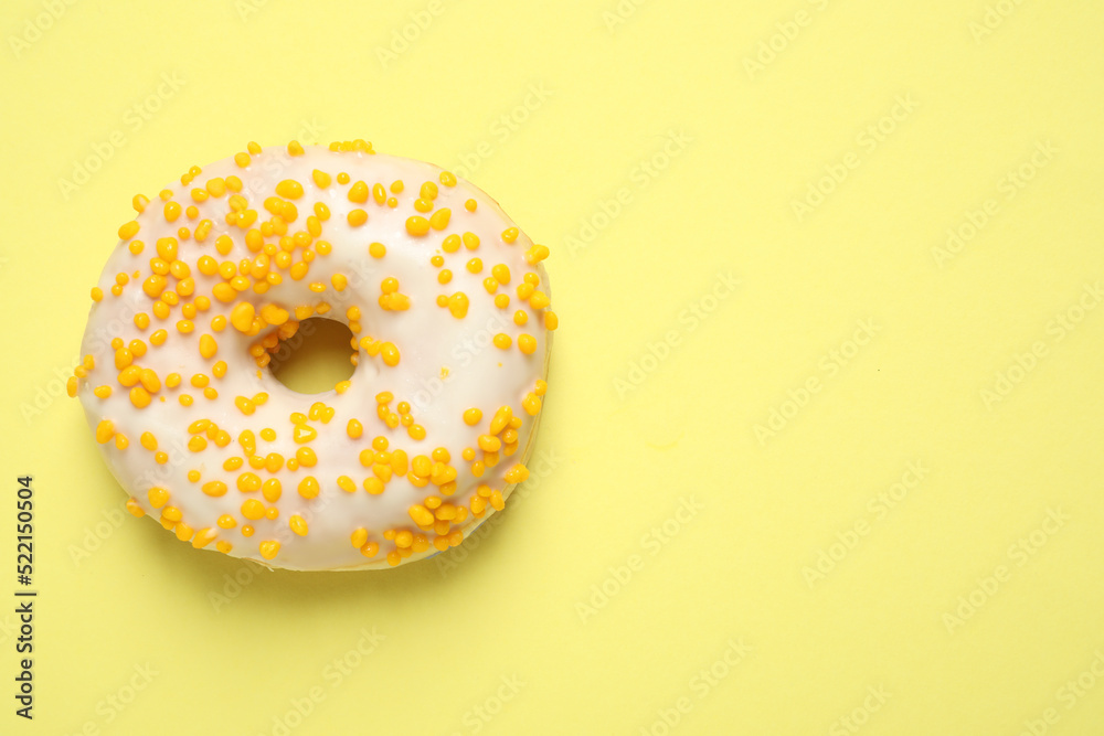 Delicious glazed donut on yellow background, top view. Space for text