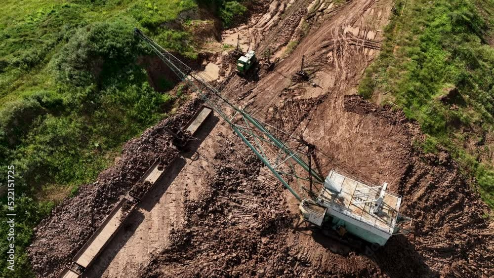 Openpit mining. Dragline excavator load clay in freight train. Clay