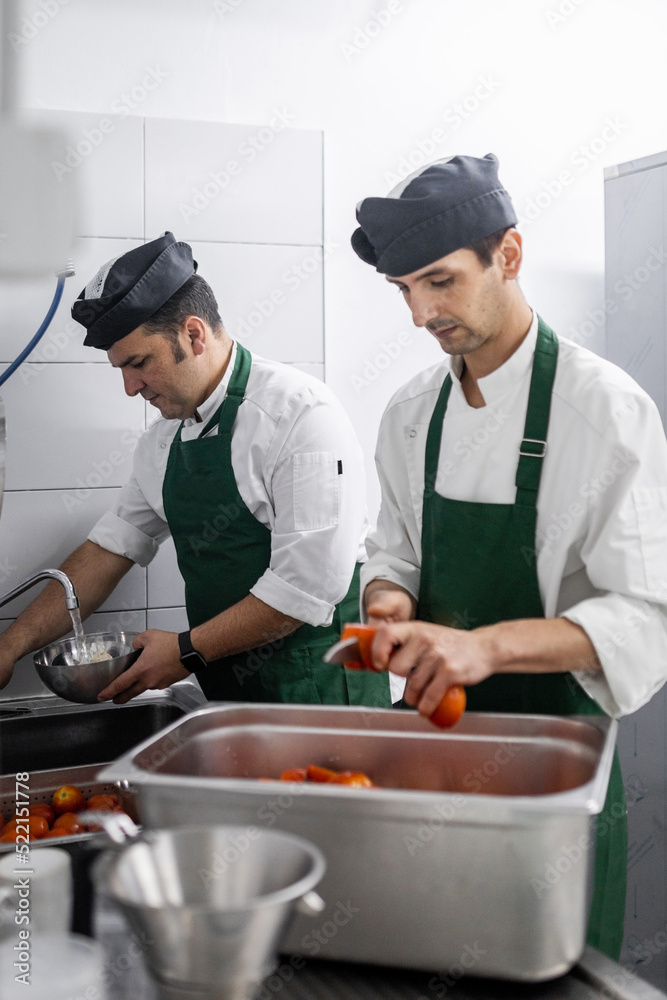 cooks cutting and washing vegetables in a restaurant kitchen cooks cutting and washing vegetables in a restaurant kitchen