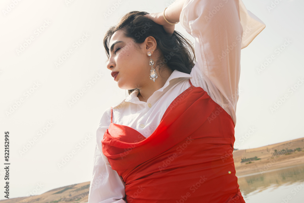 Beautiful young girl with long black hair wearing red dress in nature ...