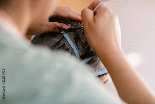 Hairdresser removing hair from highlight cap