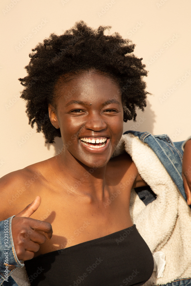 Woman putting denim jacket on and laughing Woman putting denim jacket on and laughing