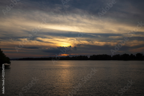 Sunset on a wide river, dramatic sky and cloud formations, nobody