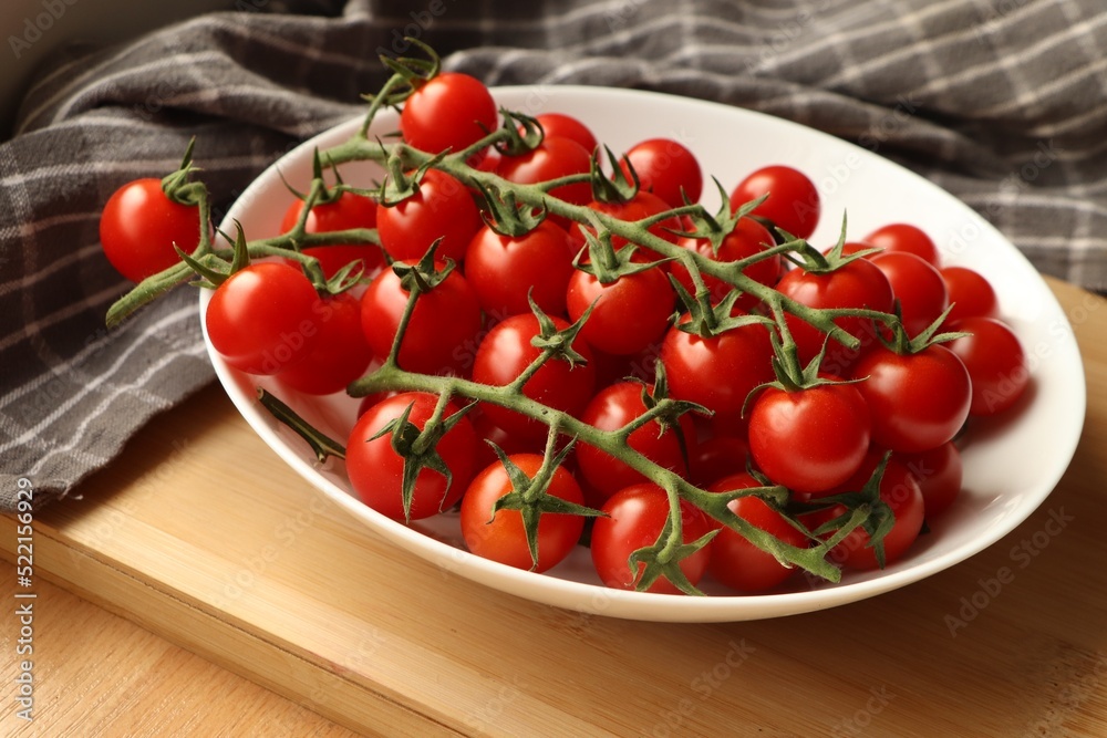 Plate of ripe whole cherry tomatoes on wooden table, closeup Plate of ripe whole cherry tomatoes on wooden table, closeup