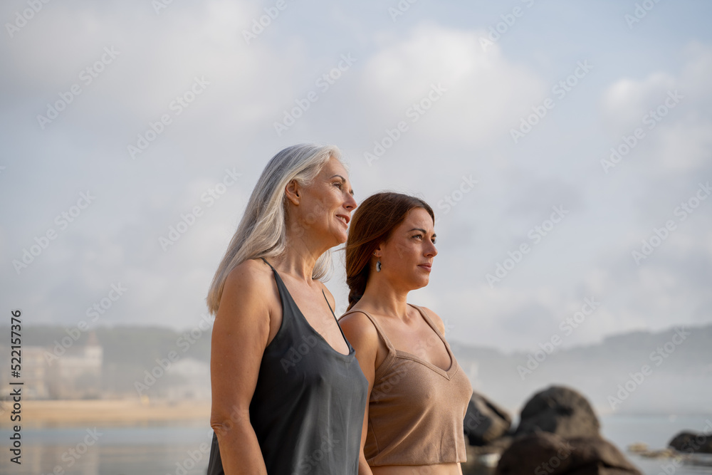 happy mother and adult daughter walking at the beach happy mother and adult daughter walking at the beach