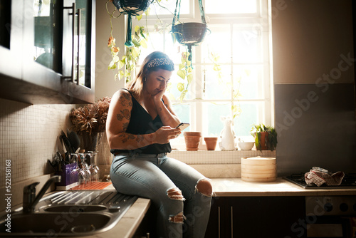Worried woman reading fake news on phone, searching social media or receiving bad news on technology during lockdown. Browsing or texting while looking stressed, concerned and anxious in home kitchen