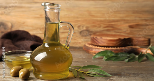 Decanter and bowl of fresh olive oil on wooden background