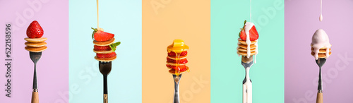 Set of forks with sweet mini pancakes and strawberry on color background