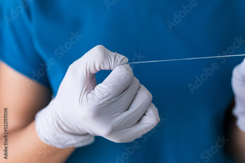 A dentist with gray gloves and blue uniform holding dental floss  photo