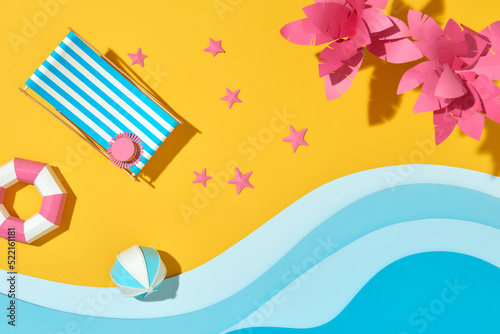 Lounge chair with parasol, palms, ring and beach ball on the coast photo