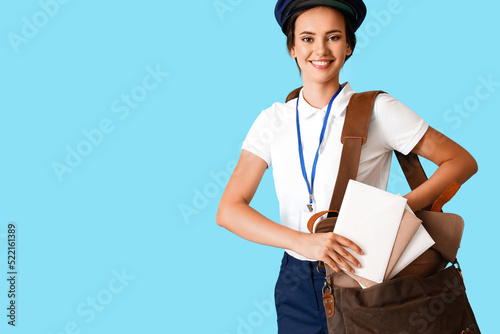 Young postwoman with letters and bag on blue background