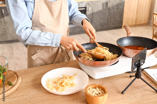 Young woman putting pasta o...