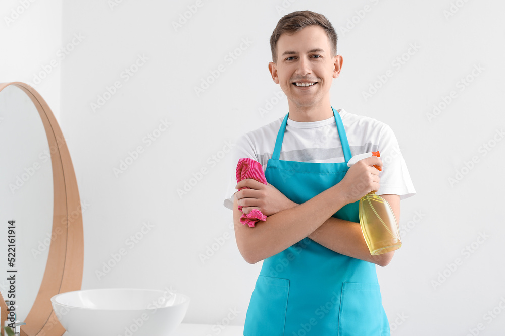 Young man with rag and detergent in bathroom Young man with rag and detergent in bathroom