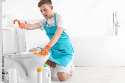Young man cleaning toilet b...