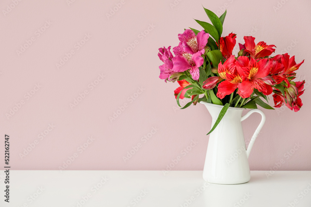 Vase with bouquet of beautiful alstroemeria flowers near color wall