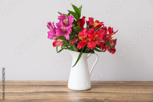 Vase with beautiful alstroemeria flowers on wooden table