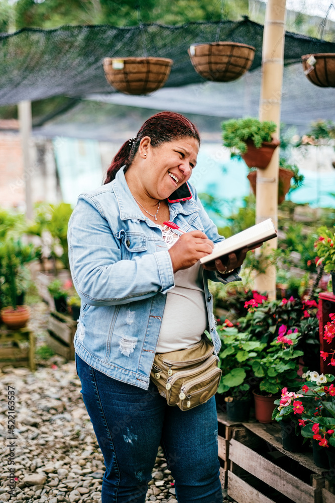 Happy mature woman taking an order at the nursery Happy mature woman taking an order at the nursery