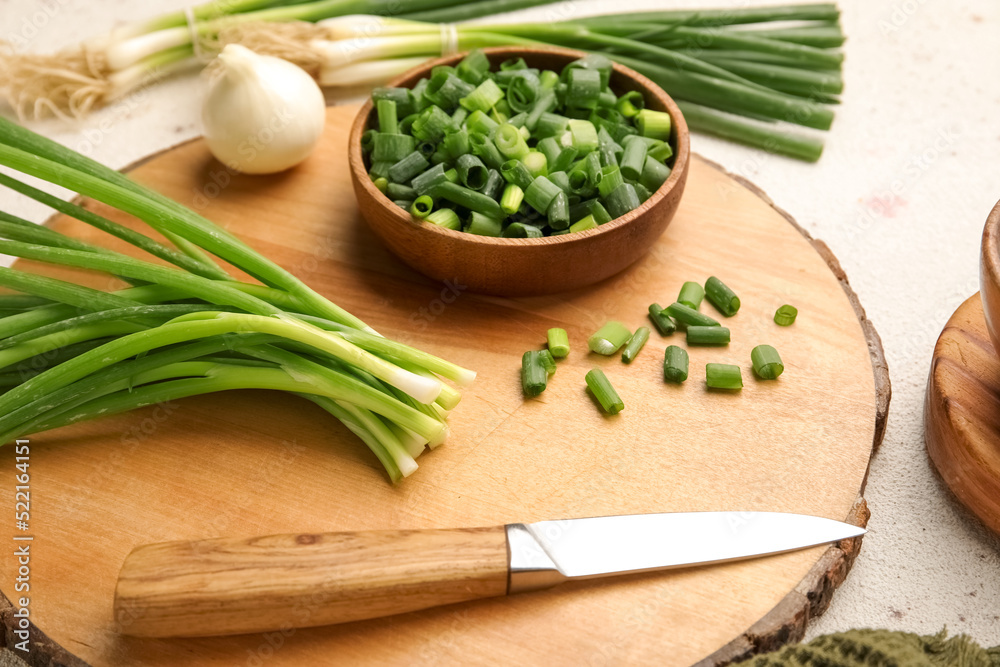 Wooden board with bunch of green onion and knife on table, closeup Wooden board with bunch of green onion and knife on table, closeup