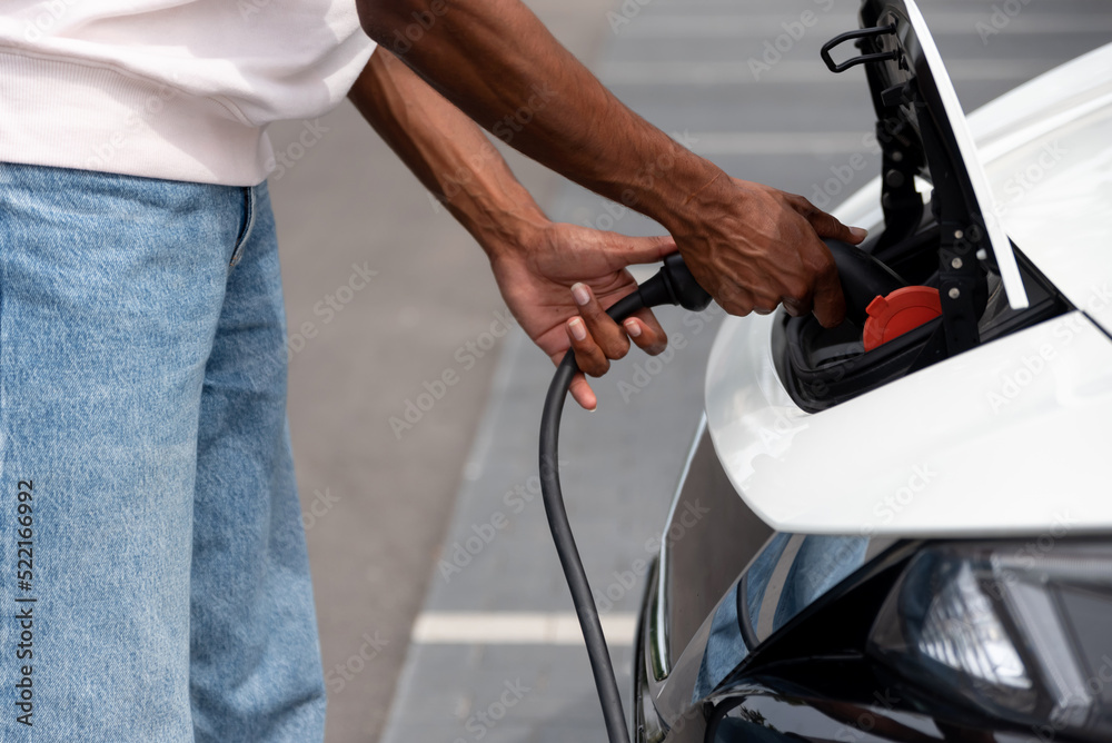 Anonymous black man charging an electric car Anonymous black man charging an electric car