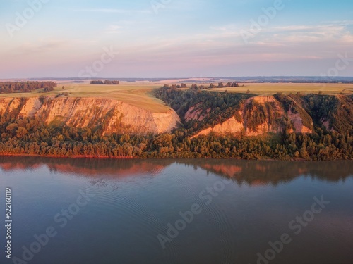 Fototapeta Naklejka Na Ścianę i Meble -  Clay coast with groves of birch trees, soil erosion, sunset clouds and the Ob riverbed