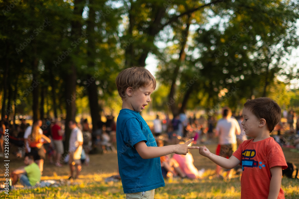 Kids are playing Rock, paper, scissors game in a park full of people