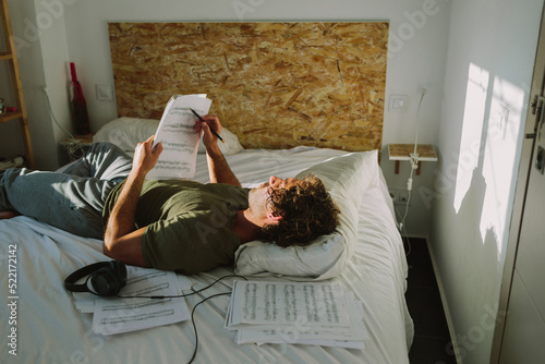 Man on a bed reading music sheet photo
