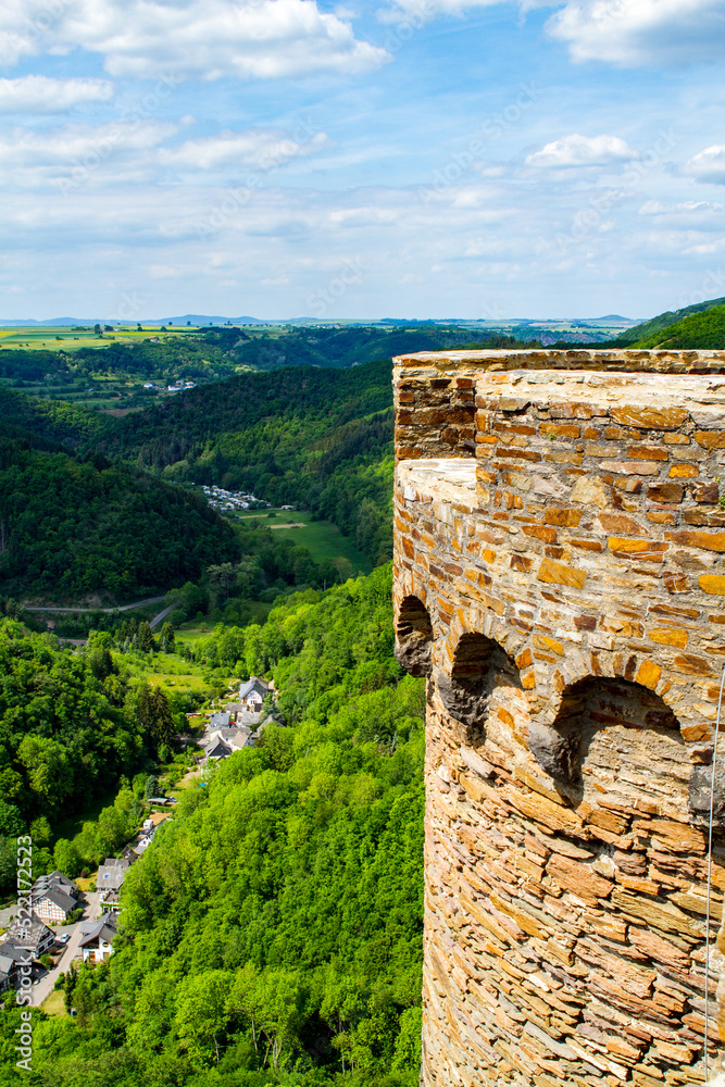 View from ruined castle in Germany on summer day looking over beautiful green valley with blue sky and white clouds.