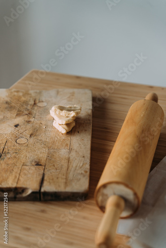 Pieces of dough on a wooden board and a rolling pin.