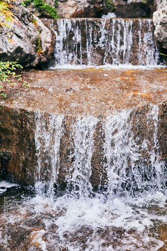 Water flows over the rocks  a waterfall in the garden. Vertical photo.