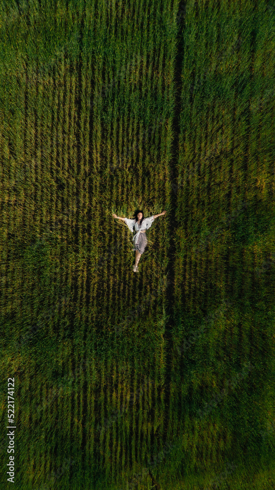young female laying on the grass with her hands spread like wings young female laying on the grass with her hands spread like wings