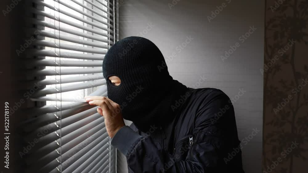 Burglar looking out the window blinds. Burglar looking out the window blinds.