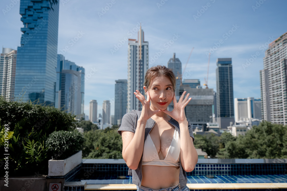 Portrait of beautiful young woman relaxing with city view, wearing white bikini and long leg jeans.