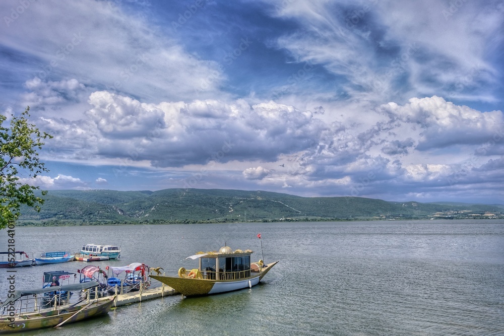 beautiful view of lake uluabat and name of city golyazi (Gölyazı), ancient boat on lake under cloudscape.