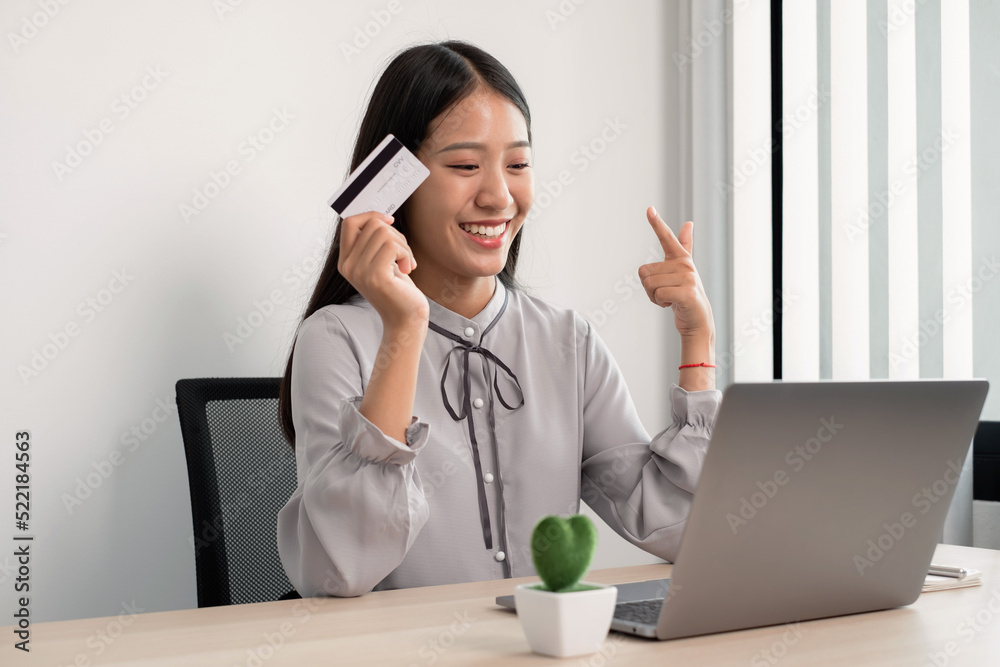The Asian businesswoman's hand is holding a credit card and using a laptop for online shopping and internet payment in the office The Asian businesswoman's hand is holding a credit card and using a laptop for online shopping and internet payment in the office