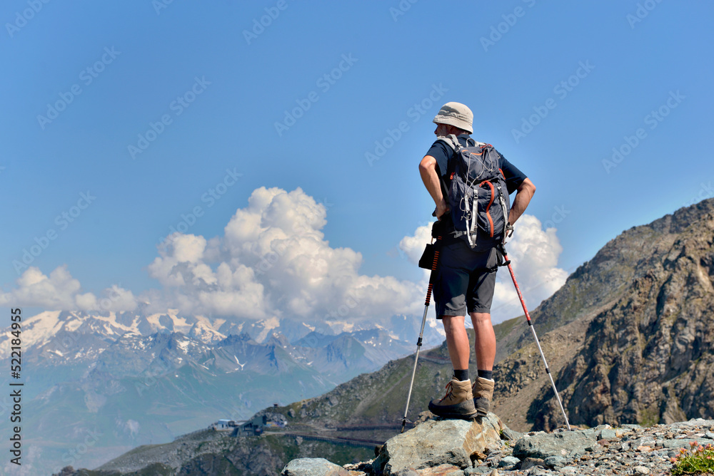 hiker standing and watching the landscape at the top of mountains in European Alps
